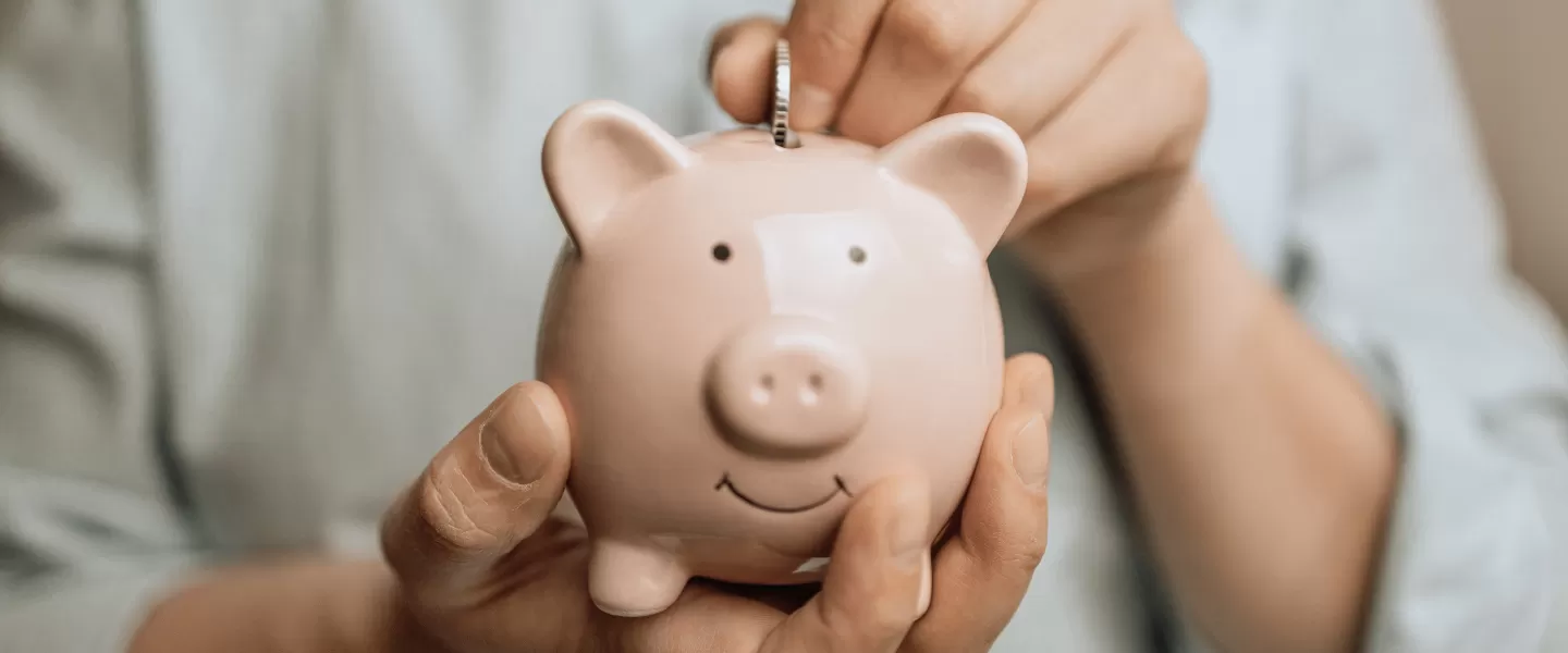 mężczyzna wrzucający monetę do skarbonki